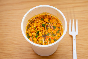Hot and spicy instant noodle cup ready to eat on the wooden table close up.