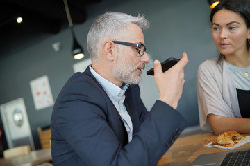 Salesman and manager working on computers and cellphone in modern office