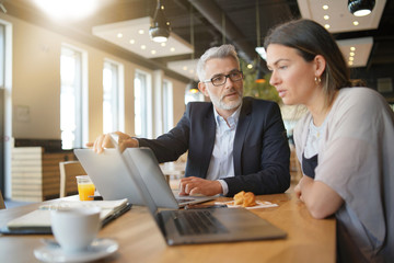 Salesman and manager working on computers during informal business meeting