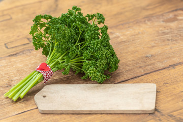 Herz und ein Bund Petersilie zur Petersilienhochzeit mit leerem Holzschild