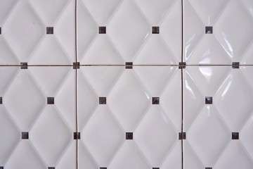 Close up of rhombus and little black square pattern of white ceramic tiles wall background in home interior decoration concept