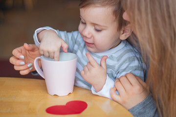 happy blonde mom and her little funny son rest in the cafe, drink tea and eat pies, have fun and have a nice family day together. selective focus, noise effect