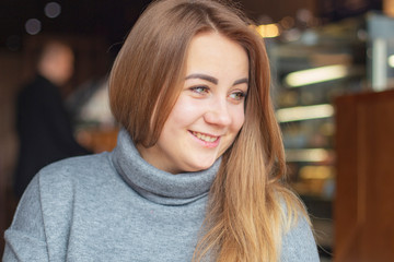 lifestyle, authentic, candid photo of face of a woman. a portrait of a beautiful woman with light hair, posing for a photo in the cafe interior