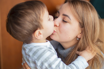 Happy mother hugs and kisses her son, a little good boy. The family rest in the cafe, they eat desserts, drink drinks, laugh and play, happy family day. selective focus, noise effect