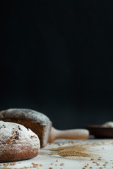 still hot bread at the  table with wheat grain in flour. background black wall concrete
