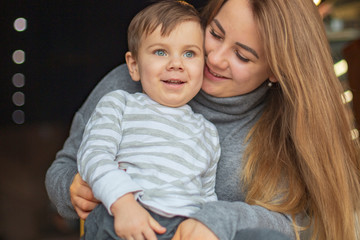 happy family, blonde mother and her beautiful and charismatic little son, the boy is having fun day in a cozy cafe. selective focus, noise effect