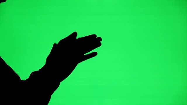 The Silhouette Of A Man Rubbing His Hands Together On A Green Screen Background.