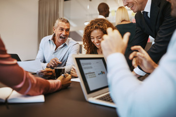 Diverse businesspeople laughing while meeting together in an off