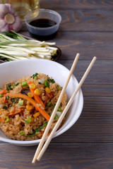 japanese food on a wooden table, fried rice with vegetables,  chopsticks. Asian/Japanese food.