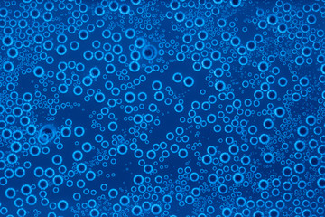 Background of bubbles of sparkling water in blue light