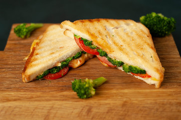Broccoli cheese sandwiches on wooden cutting board, on concrete, slate background