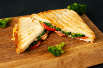 Broccoli cheese sandwiches on wooden cutting board, on concrete, slate background