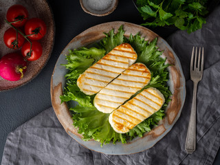 Grilled Halloumi, fried cheese with  lettuce salad.  Balanced diet on  dark background, top view
