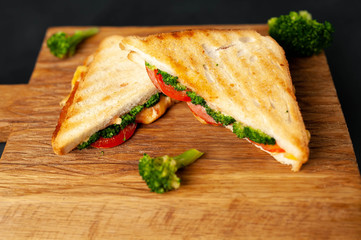 Broccoli cheese sandwiches on wooden cutting board, on concrete, slate background