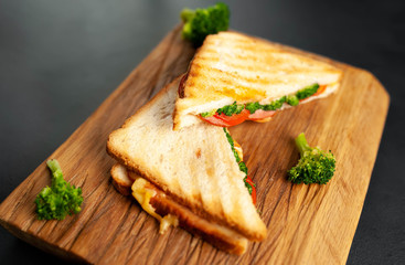 Broccoli cheese sandwiches on wooden cutting board, on concrete, slate background