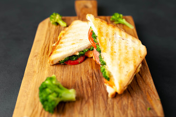 Broccoli cheese sandwiches on wooden cutting board, on concrete, slate background