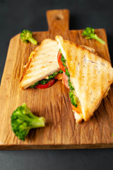 Broccoli cheese sandwiches on wooden cutting board, on concrete, slate background