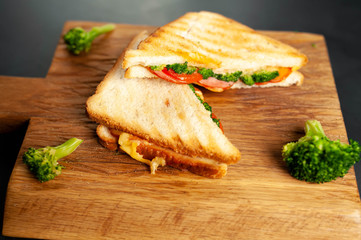 Broccoli cheese sandwiches on wooden cutting board, on concrete, slate background