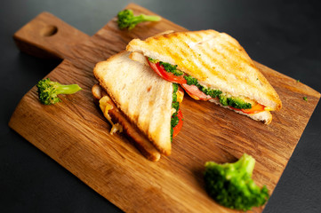 Broccoli cheese sandwiches on wooden cutting board, on concrete, slate background