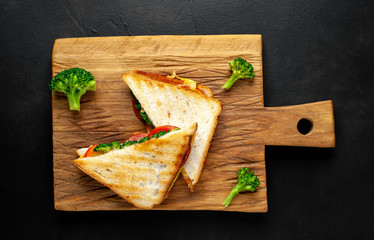 Broccoli cheese sandwiches on wooden cutting board, on concrete, slate background