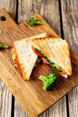 Broccoli cheese sandwiches on wooden cutting board, on wooden table