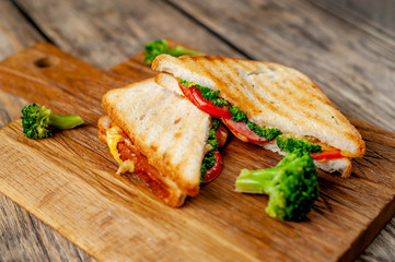 Broccoli cheese sandwiches on wooden cutting board, on wooden table