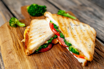 Broccoli cheese sandwiches on wooden cutting board, on wooden table