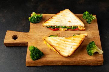 Broccoli cheese sandwiches on wooden cutting board, on wooden table