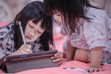 two little girls playing and learning tablet. concept digital tablet and smartphone family