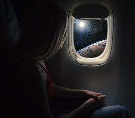 Woman in spaceship looks out the porthole. Commercial space travel concept.