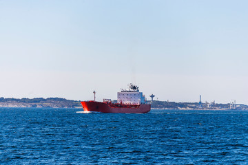 Tanker ship at sea with a refinery in the background