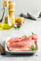 Raw pork chops, spices, herbs, olive oil. Selective focus, space for text.