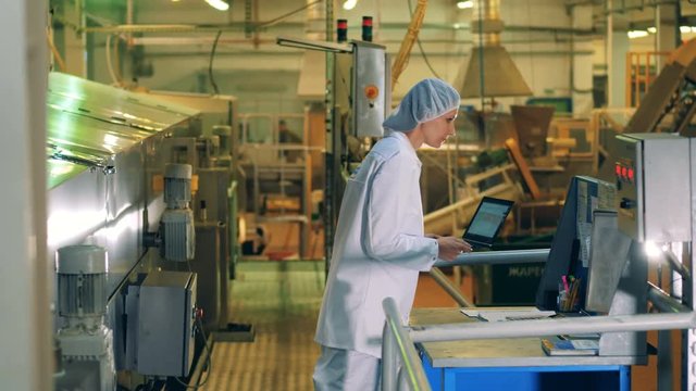 A Woman Works With A Laptop At A Food Production Factory.