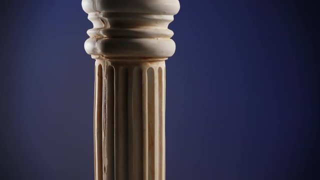 Single ancient greek column rotating slowly on dark blue background