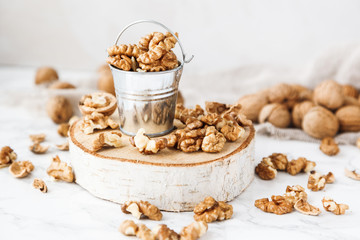 A bucket of walnuts on a marble table.
