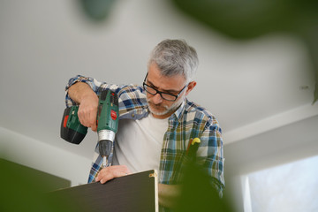 Mature man using power drill at home
