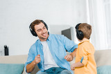 happy father with preschooler son in headphones listening music at home