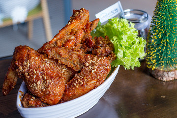 Yangnyean Chicken Wing coated with crushed nuts and lettuce on the side