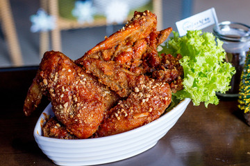 Yangnyean Chicken Wing coated with crushed nuts and lettuce on the side