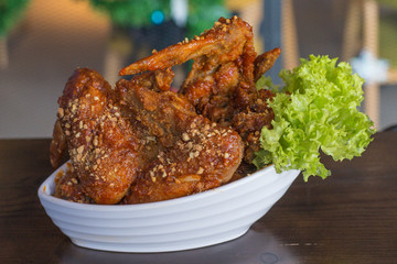 Yangnyean Chicken Wing coated with crushed nuts and lettuce on the side