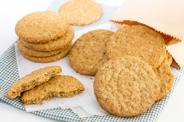 Homemade shortbread cookies made of oatmeal are stacked on cloth and in paper bag on white table background. Concept food healthy snack for enjoy in holiday.