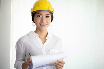 Asian women engineering inspecting and working and holding blueprints at office