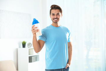 Young man with bottle of protein shake at home