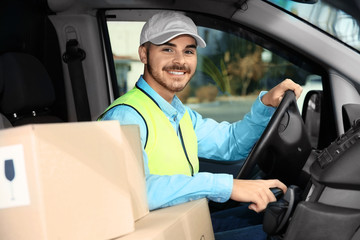 Young courier driving delivery van with parcels