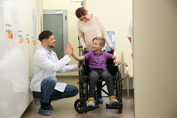 Doctor with woman and her child in wheelchair at hospital