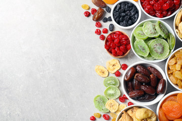 Bowls of different dried fruits on grey background, top view with space for text. Healthy food