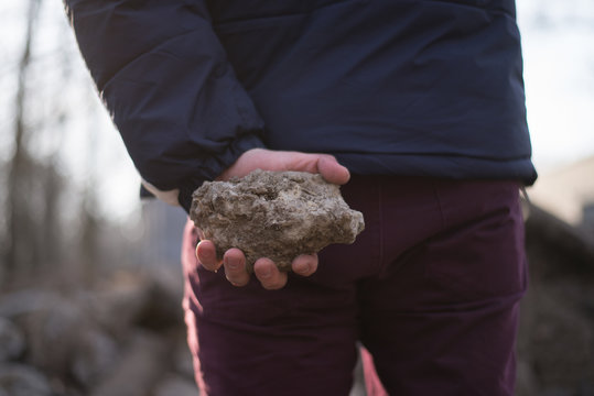 man holds stone behind his back