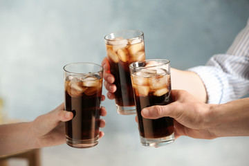 Friends with glasses of cold cola on color background, closeup
