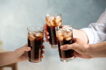 Friends with glasses of cold cola on color background, closeup