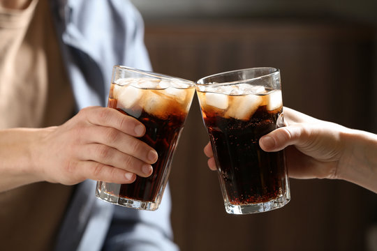 Couple with glasses of cold cola indoors, closeup